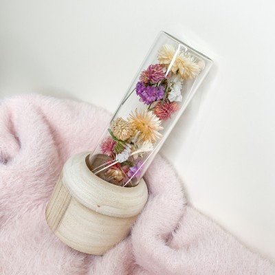 Tube en verre contenant un mélange de fleurs séchées. Format moyen.