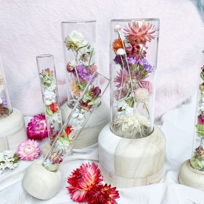 Tube en verre contenant un mélange de fleurs séchées. Format moyen.