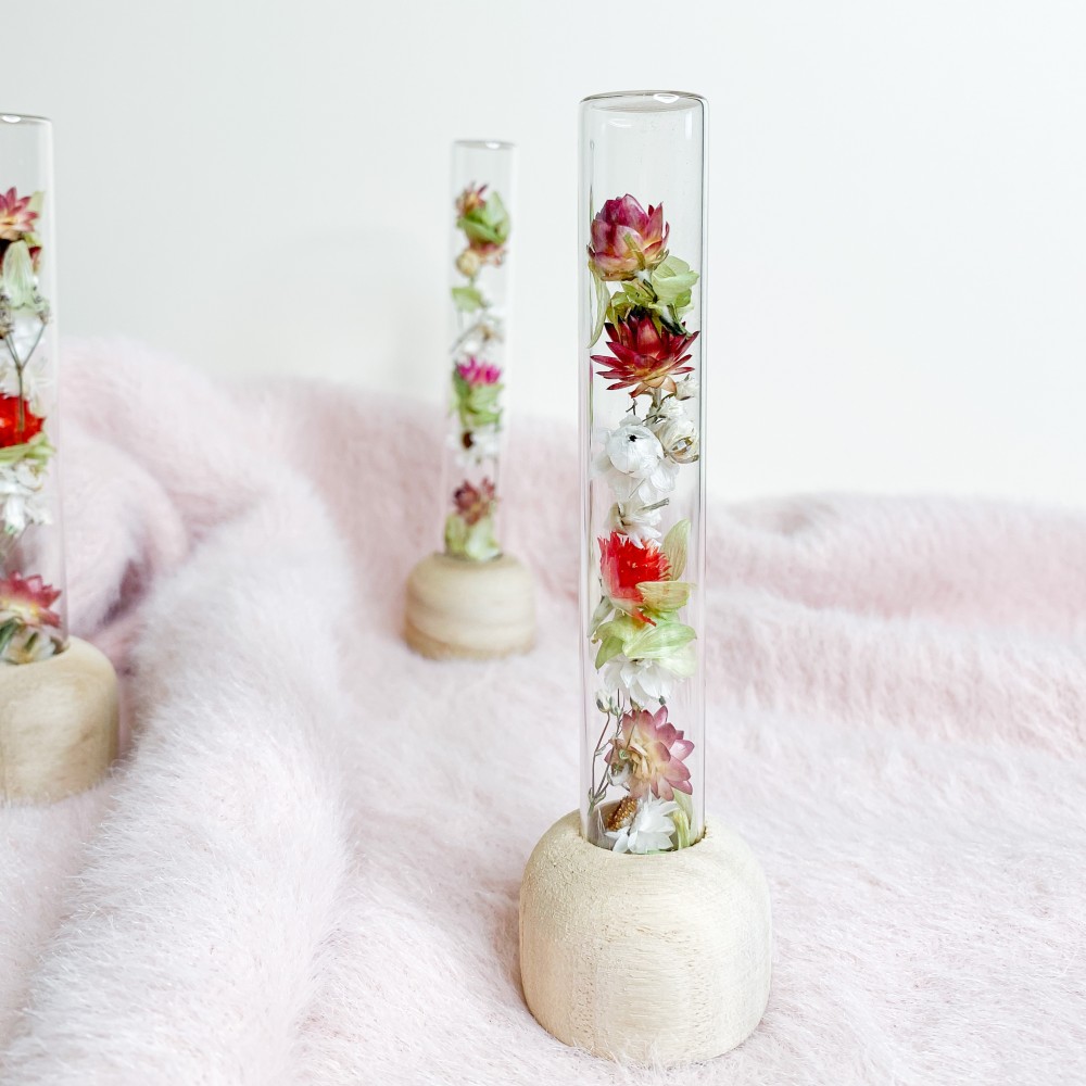 Tube en verre contenant un mélange de fleurs séchées. Format moyen.