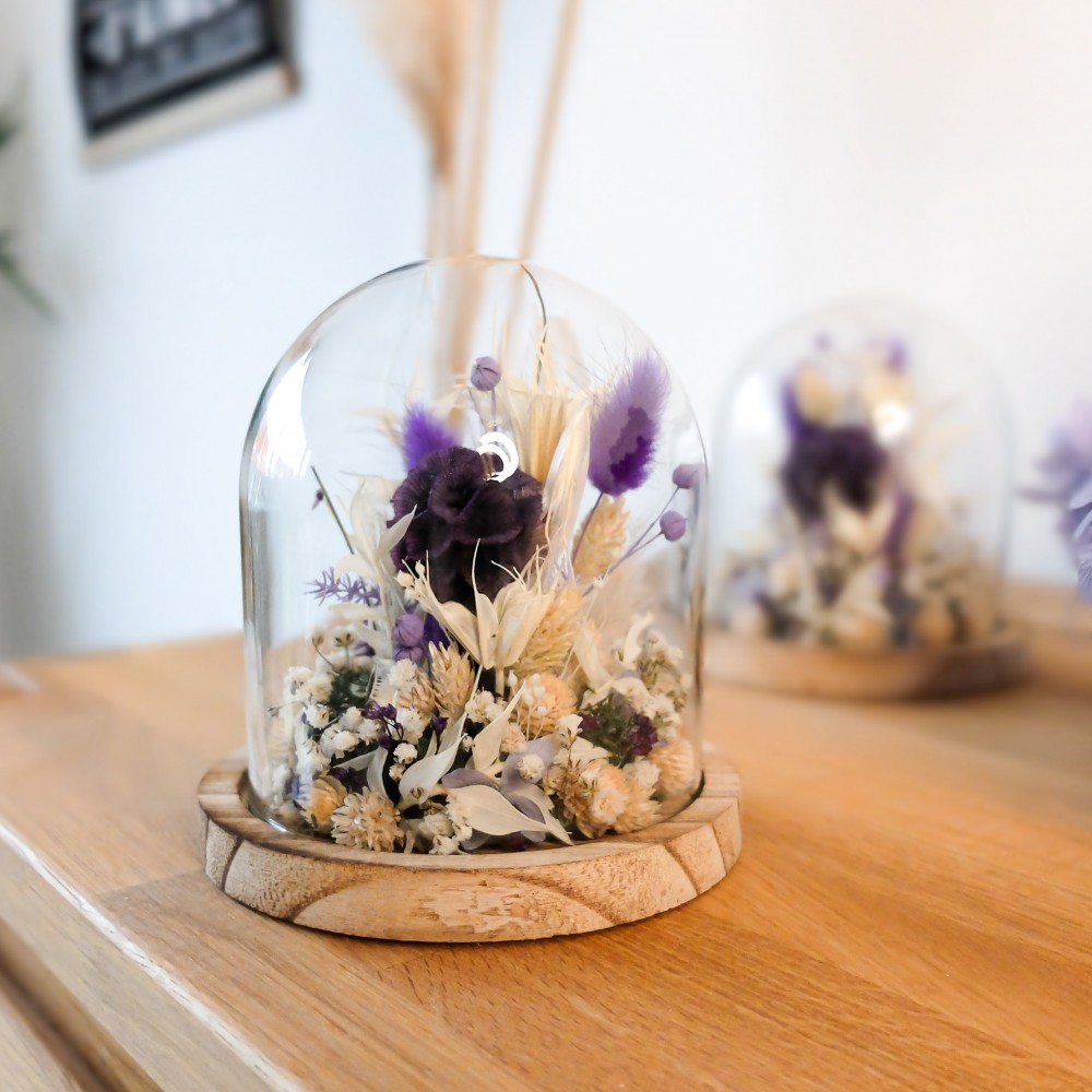Cloche en verre et base en bois contenant des fleurs séchées crème, parme et violet. Petit format. Collection Milka