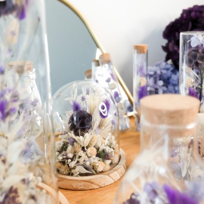 Cloche en verre et base en bois contenant des fleurs séchées crème, parme et violet. Petit format. Collection Milka