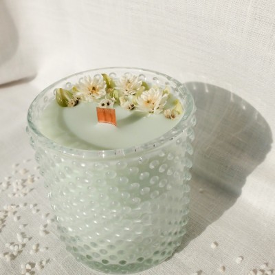 Bougie parfumée à la fleur de coton et décorée de fleurs séchées. Mèche en bois.