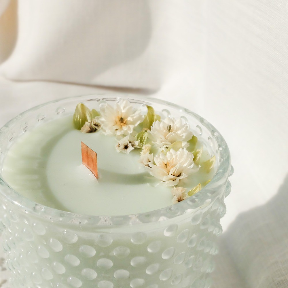 Bougie parfumée à la fleur de coton et décorée de fleurs séchées. Mèche en bois.