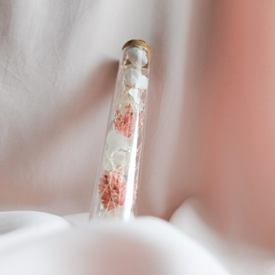 Tube en verre contenant des fleurs séchées blanc et rose. Petit format.