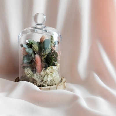 Cloche en verre et base en bois contenant des fleurs séchées crème, rose et vert. Petit format.