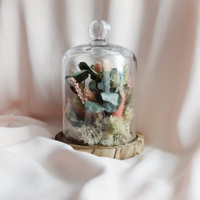 Cloche en verre et base en bois contenant des fleurs séchées crème, rose et vert. Petit format.