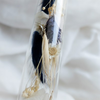 Tube en verre contenant des fleurs séchées blanc et bleu. Petit format.