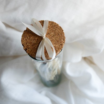 Fiole en verre contenant un bouquet suspendu crème et vert.