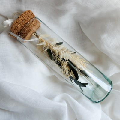 Fiole en verre contenant un bouquet suspendu crème et vert.