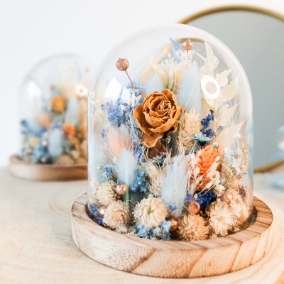 Cloche en verre et base en bois contenant des fleurs séchées blanches, pêche et bleu ciel. Petit format. Collection Pêche Bleue