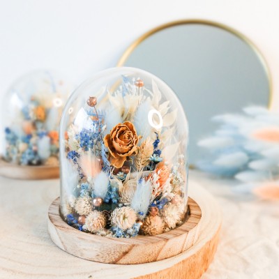 Cloche en verre et base en bois contenant des fleurs séchées blanches, pêche et bleu ciel. Petit format. Collection Pêche Bleue