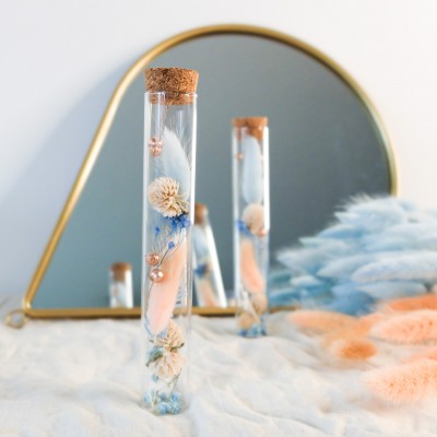 Tube en verre contenant des fleurs séchées blanches, pêche et bleu ciel. Petit format. Collection Pêche Bleue