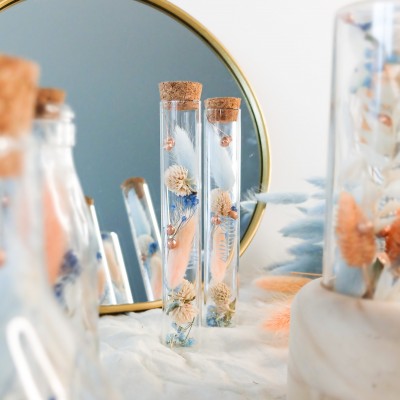 Tube en verre contenant des fleurs séchées blanches, pêche et bleu ciel. Petit format. Collection Pêche Bleue