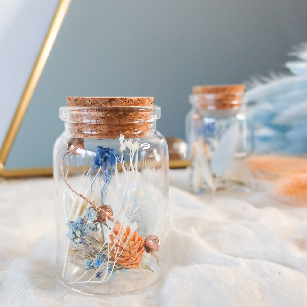 Fiole en verre contenant des fleurs séchées blanches, pêche et bleu ciel. Petit format. Collection Pêche Bleue