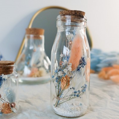 Fiole en verre contenant des fleurs séchées blanches, pêche et bleu ciel. Format moyen. Collection Pêche bleue