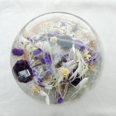 Cloche en verre et base en bois contenant des fleurs séchées blanches et violettes